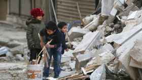 A file photo shows children collecting firewood amid damage and debris at a site hit yesterday by airstrikes in the rebel held al-Shaar neighbourhood of Aleppo